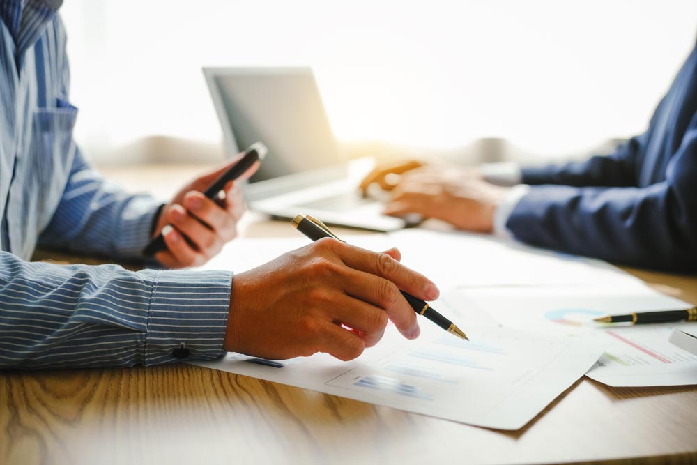 Business tax and audit consulting services. Business Consulting - two people at a desk working.